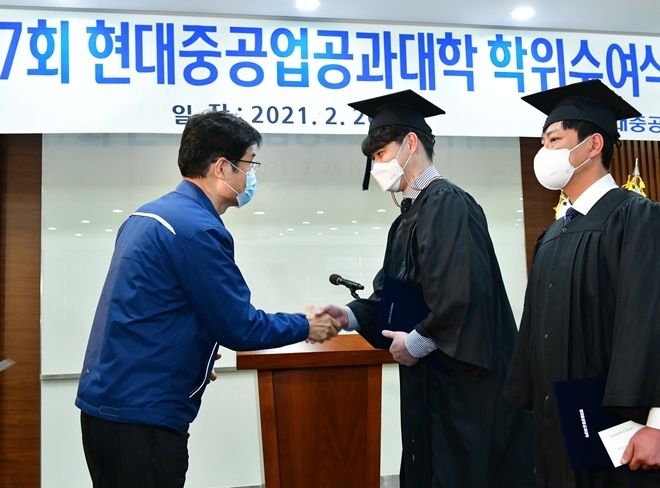 26일 진행된 현대중공업공과대학 제7회 학위수여식. 현대중공업공과대학 이상균 학장이 기계전기학과대표 정민욱(현대건설기계) 사우, 조선해양학과 대표 정충국(현대중공업) 사우에게 학위증서를 수여하고 악수를 나누고 있다.(사진제공=현대중공업)