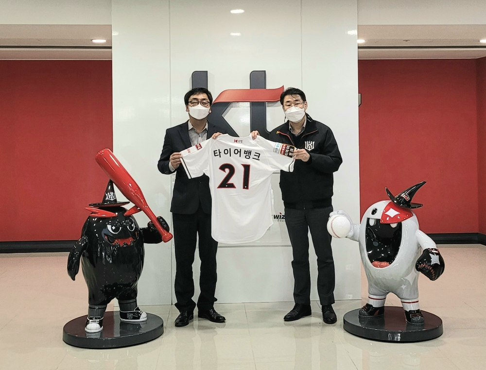 타이어뱅크 홍보마케팅본부 김재현 이사(왼쪽) 와 kt sports 경영기획실 이인원 실장(오른쪽)이 경기도 수원에 있는 kt wiz park에서 진행된 후원 협약식을 마치고 2021년 시즌을 뜻하는 21번 유니폼 백넘버를 들고 기념촬영을 하고 있다.(사진=타이어뱅크)