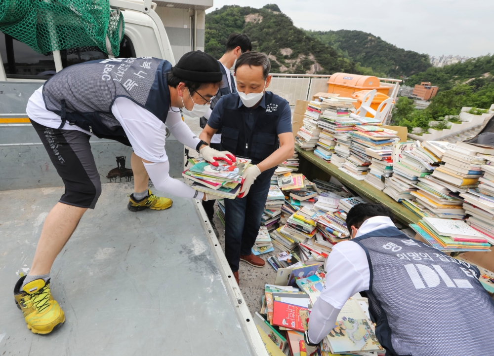 DL이앤씨 이규성 주택사업 본부장(가운데)과 직원들이 서울시 종로구에 위치한 선덕원에서 폐기물을 나르고 있다.(사진=DL이앤씨)