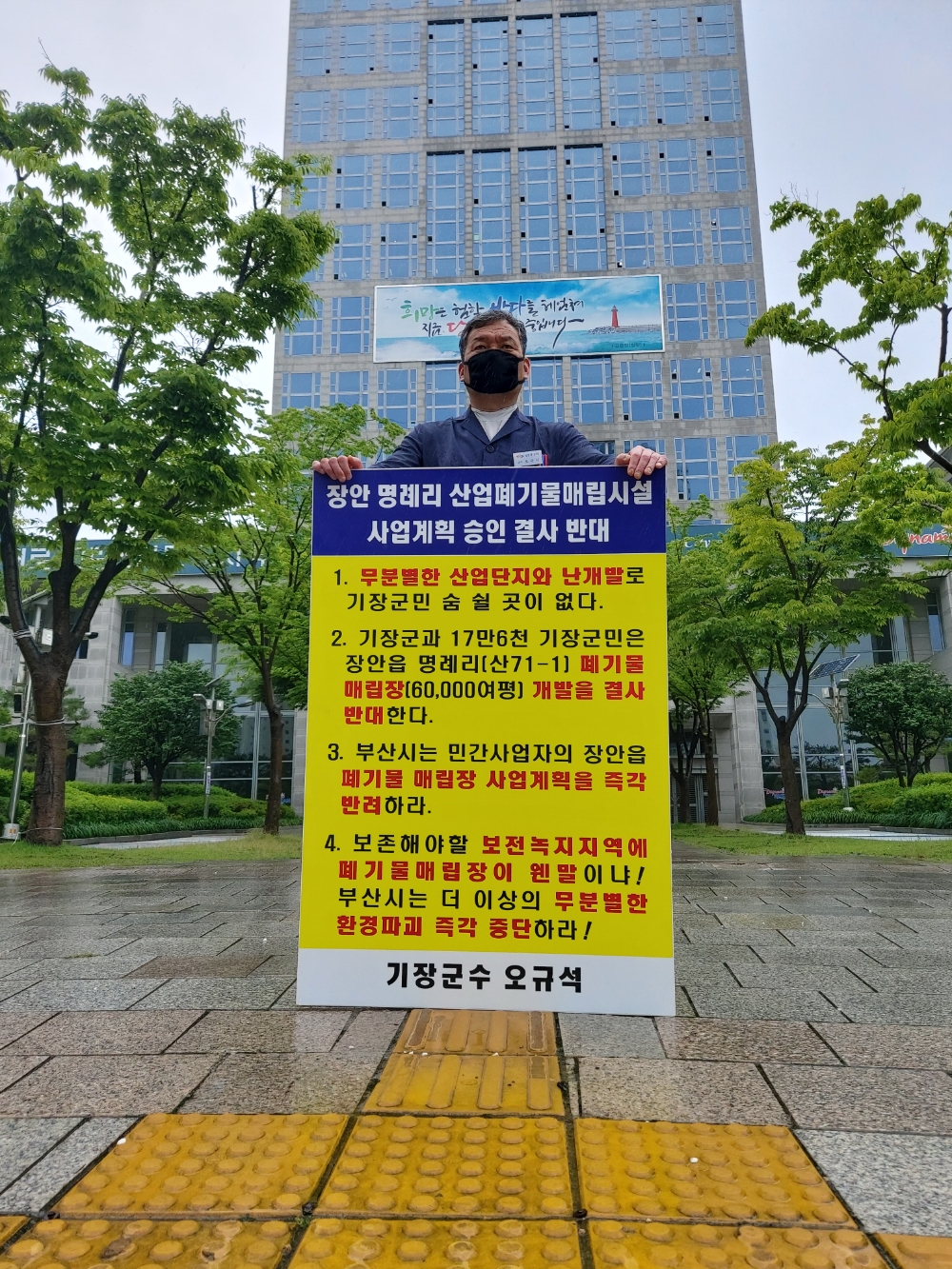 부산 기장군수가 12일 오전 11시 부산시청 앞에서 장안읍 명례리 산업폐기물 매립시설 사업계획 승인 결사반대를 외치며 빗속에서 1인 시위 중이다.(사진제공=부산 기장군)