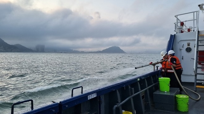출동한 해경이 소화포를 이용 기름띠 분산 작업을 하고 있다.(사진제공=부산해양경찰서)