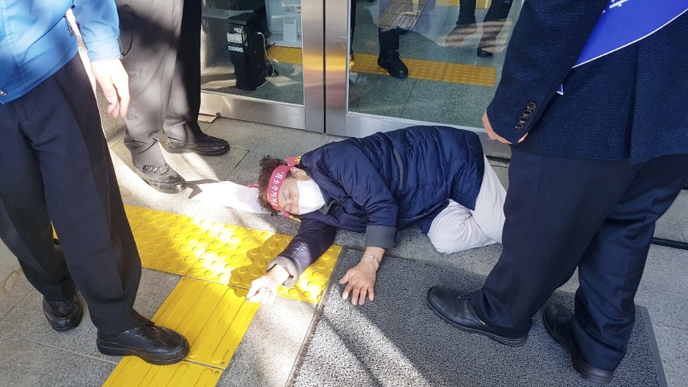 화수·화평재개발조랍원이 시위를 하다 실신하여 바닥에 누워있다.