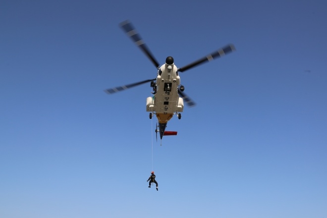 남해해경청 소속 헬기에서 중앙해양특수구조단 구조사가 호이스트를 이용한 인명구조합동훈련을 실시하고 있다.(사진제공=남해지방해양경찰청)
