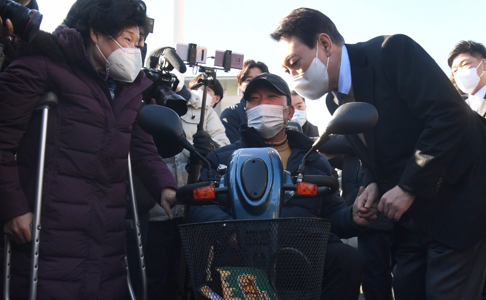 국민의힘 윤석열 대선후보가 13일 중앙선대위 장애인 복지지원본부가 개최한 전국 릴레이정책투어 '장문현답(장애인 문제의 답은 현장에 있다)' 출정식에서 참석자들과 대화를 나누고 있다. 사진=연합뉴스