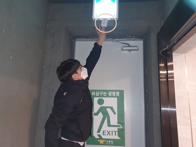 비상구 인근 장애물 적치시 음량경보를 송출해 불법행위를 근절하는 '비상구 무인안전지킴이'를 설치하고 있다(사진제공=부산소방재난본부)