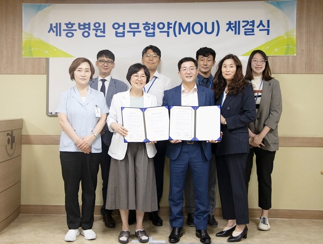 세흥병원 권오숙 행정원장과 부산남부교육지원청 변용권 교육장이 업무협약서를 내보이며 직원들과 기념촬영.(사진제공=부산교육청)