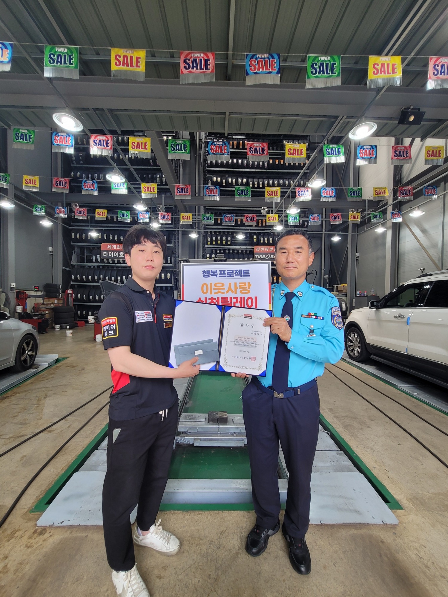 9일 충북 청주시 서원구 미평동에 위치한 타이어뱅크 분평점 김상원 사업주(좌)와 김학교씨(우)가 이웃사랑 실천 릴레이 증정식을 마치고 기념 촬영을 하고 있다.(사진=타이어뱅크)
