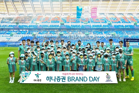 하나증권브랜드데이를 맞아 축구경기 전 대전하나시티즌 선수들이 임직원 자녀들과 함께 기념촬영을 하고 있다. 사진=하나증권