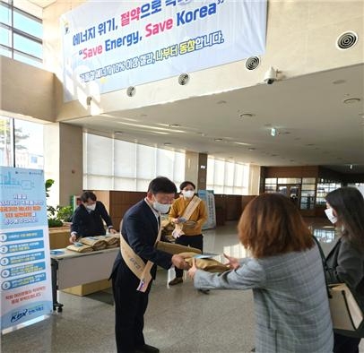 전력거래소 정동희 이사장이 출근하는 직원들에게 무릎담요와 에너지절약 실천 안내문을 배부하고 있다.(사진=전력거래소)