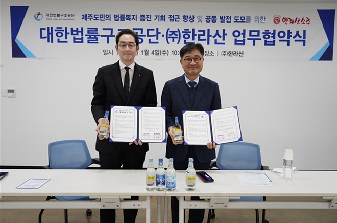 현재웅 ㈜한라산 대표이사(왼쪽)와 최보영 대한법률구조공단 제주지부장이 업무협약서를 내보이며 기념촬영.(사진제공=대한법률구조공단)