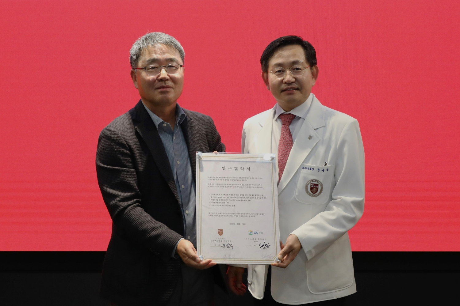GS건설 경영지원본부장 김태진 사장, 고려대학교의료원 윤을식 의무부총장이 폐안전모를 재활용한 업무협약패를 들고 기념사진을 촬영하고 있다.(사진=GS건설)