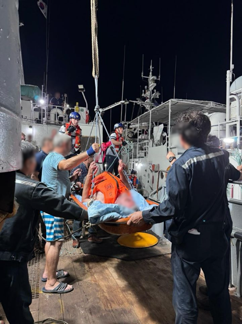 들것에 있는 응급환자를 어선 크레인을 이용해 경비함정으로 이송하는 모습.(제공=부산해경)