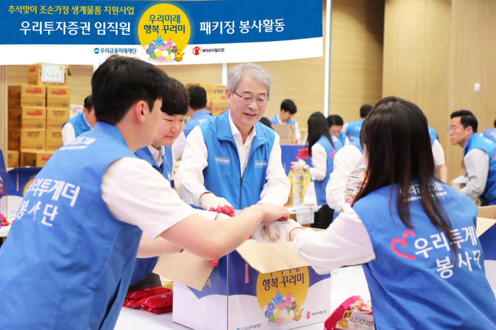 우리금융그룹 임종룡 회장(앞줄 오른쪽에서 아홉번째), 우리투자증권 남기천 대표이사(앞줄 오른쪽에서 열한번째)가 추석맞이 조손가정 생계물품 키트 포장 봉사활동에 참여한 우리투자증권 임직원들과 함께 사진을 찍고 있다. 사진=우리금융지주