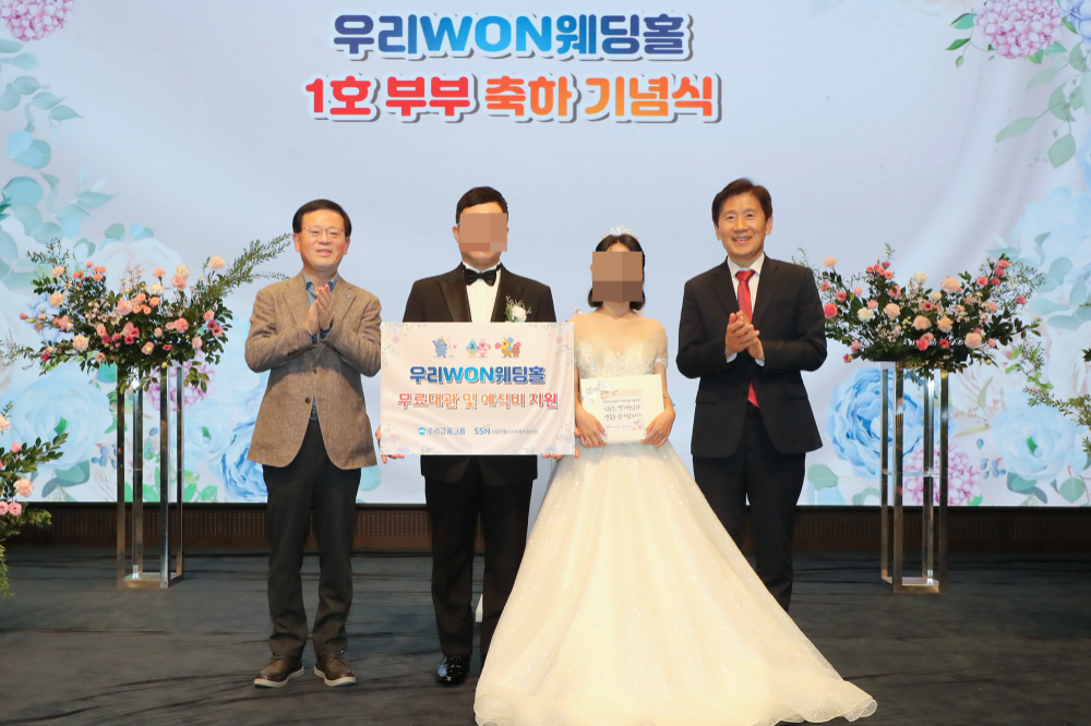 지난 13일 취약계층 신혼부부의 결혼식을 위해 우리금융 본사 사옥 웨딩홀을 무료로 대관해 주는 ‘우리 WON 웨딩홀’ 1호 부부가 탄생했다. (왼쪽부터) 조병규 우리은행장, ‘우리 WON 웨딩홀’ 1호 부부, 김현훈 서울특별시사회복지협의회장이 기념촬영을 하고 있다. 사진=우리금융그룹