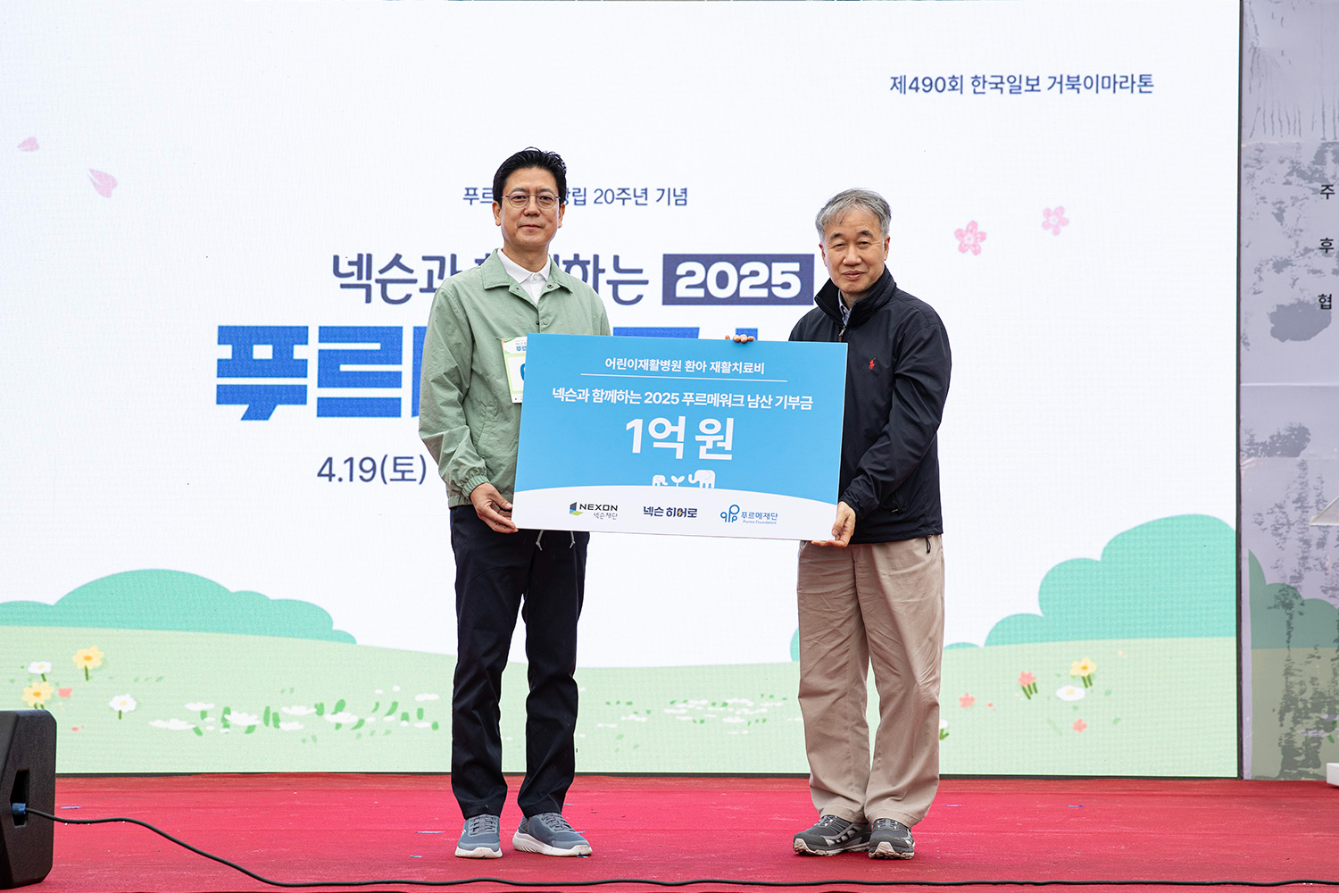 19일 서울 중구 남산 백범광장에서 진행된 ‘넥슨과 함께하는 2025 푸르메워크 남산’ 대회에서 넥슨재단 김정욱 이사장(왼쪽)과 푸르메재단 백경학 상임대표가 기부금 전달식을 진행하고 있다. 사진=넥슨