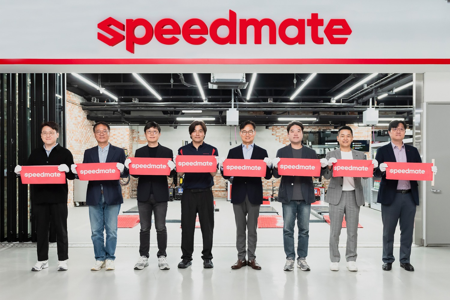 스피드메이트 강동아이파크점에서 신규 로고와 함께 기념사진을 촬영하고 있는 안무인 SK스피드메이트 대표(오른쪽 네번째) 등 사업부서 관계자들의 모습.(사진=SK스피드메이트)