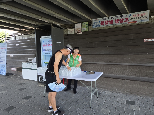 도봉구 주민이 중랑천 상계교 하부에 마련된 봉달샘 냉장고에서 생수를 가져가고 있다.