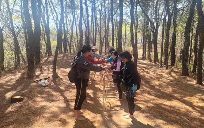 ‘구로형 정원처방’ 참가자들이 숲 속에서 나뭇가지를 활용한 체험 활동에 참여하고 있다.