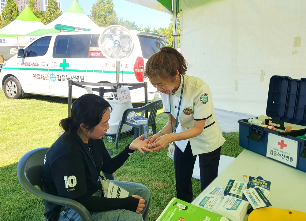 갑을녹산병원은 지난 8월 30일 부산시 강서구에서 개최된 ‘2025 강서 썸머페스티벌’에 구급차 및 의료부스를 지원하고 의료진이 행사에 참여한 진행요원의 상처를 치료하고 있다.(사진=KBI그룹)