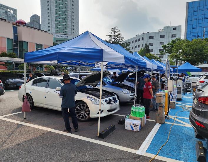 차량 상태를 확인 중인 정비사와 점검을 받는 주민들의 모습