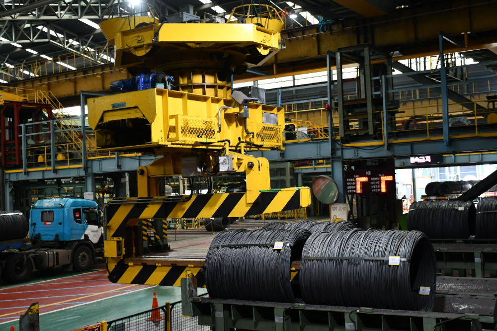 크레인이 선재 코일의 중심점 위치를 추적해 제품 야드에서 제품을 들어올리고 있다.(포스코DX)