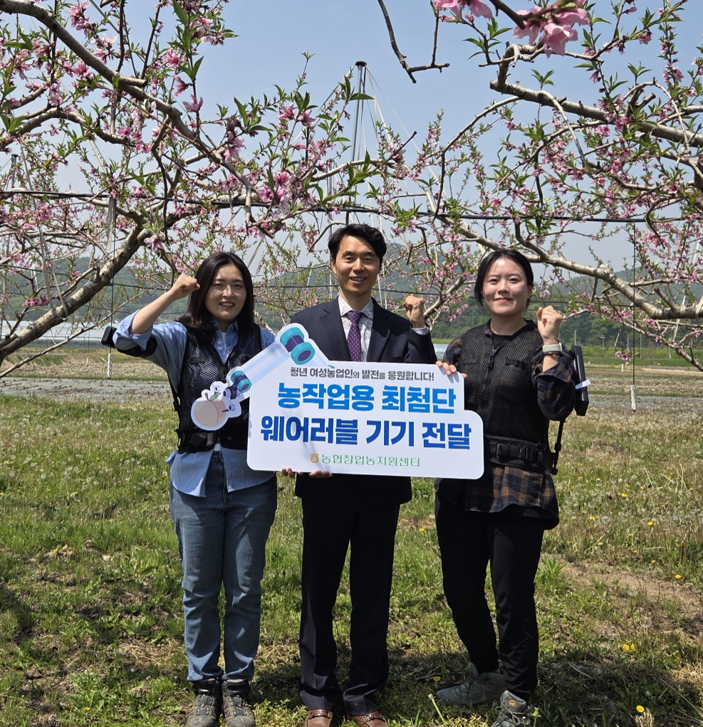 27일 충북 음성군 복숭아 농장에서 서종경 창업농지원센터장(사진 가운데)이 청년 여성농업인에게 농작업용 최첨단 웨어러블 기기를 전달하고 있다. 사진=농협중앙회