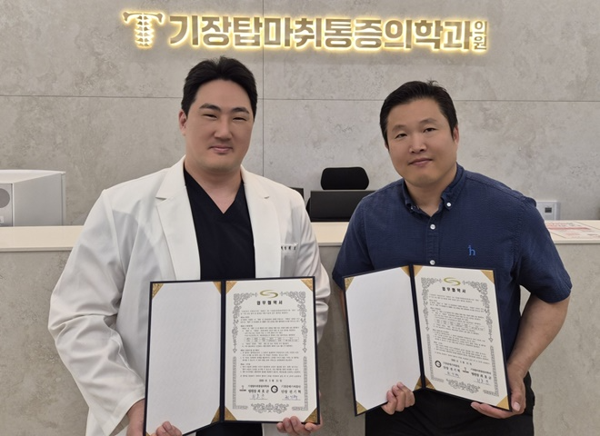 오흥민 기장갈매기 씨름단 감독(오른쪽)과 최효균 기장탑마취통증의학과 병원장(왼쪽)이 업무협약서를 내보이며 기념촬영을 하고 있다.(사진제공=부산 기장군)