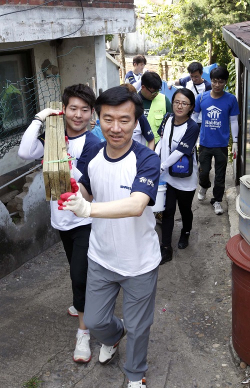 김한기 대림산업 사장(맨 앞쪽)이 희망의 집 고치기 활동을 위해 자재를 나르고 있다.