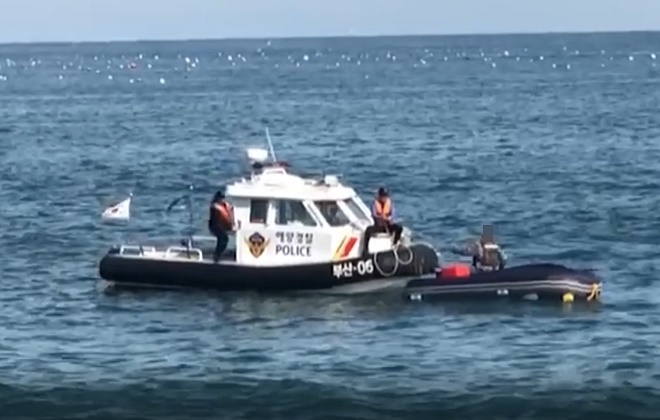 해경이 뒤집힌 고무보트 위에 있는 승선원을 구조하고 있다.(사진제공=부산해양경찰서)