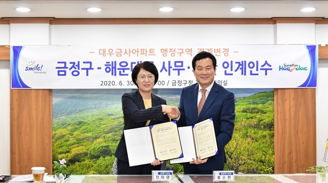 정미영 구청장과 홍순헌 해운대구청장이 30일 대우금사아파트 행정구역 경계변경에 따른 사무재산 인계인수식을 갖고 악수를 나누고 있다.(사진제공=부산 금정구)