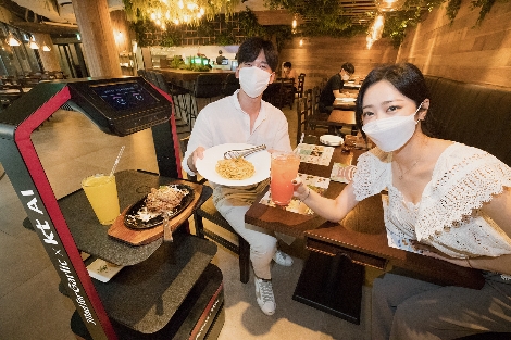 모델이 서울 강남구에 위치한 ‘매드포갈릭 봉은사 현대아이파크타워점’에서 KT AI 서빙로봇을 소개하고 있다. 사진=KT