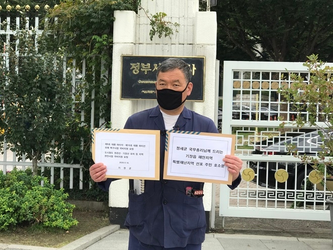 기장군수가 9월 16일 오후 1시 구윤철 국무조정실장과의 면담을 앞두고 서울 종로구 정부서울청사 정문 앞에서 기장읍 해안지역을 특별재난지역으로 선포해 달라는 17만 기장군민들의 간절한 현장의 목소리를 담은 ‘정세균 국무총리님께 드리는 기장읍 해안지역 특별재난지역 선포 주민 호소문’과 ‘제9호 태풍 마이삭·제10호 태풍 하이선 태풍 피해 복구사업 및 도시철도 정관선·기장선 유치 등 지역현안사업 국비 지원 건의문’을 내보이고 있다.(사진제공=부산 기장군)