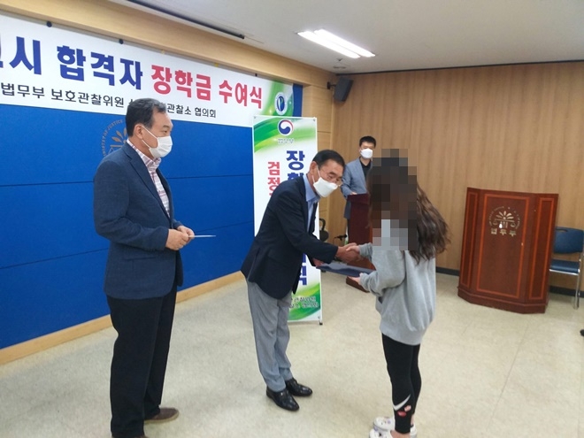 권택형 협의회장이 고졸검정고시 합격자에게 장학금을 전달하며 격려하고 있다.(사진제공=상주준법지원센터)