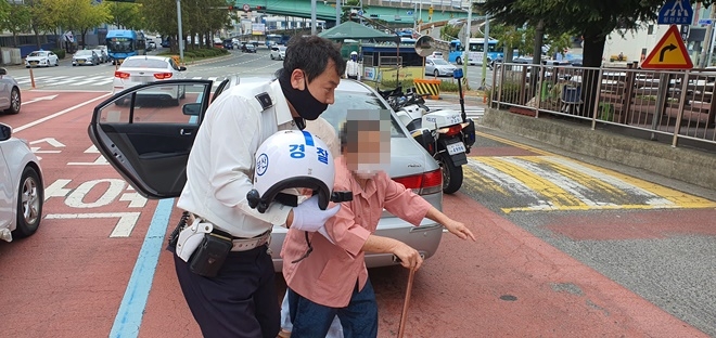 연기나는 차량 안에 있던 어르신을 안전하게 구조하고 있는 교통순찰대원.(사진제공=부산경찰청)