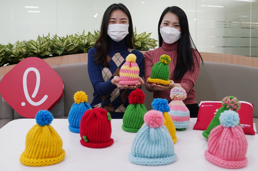 ‘신생아 모자 뜨기’ 캠페인에 참여한 롯데건설 임직원들이 직접 뜬 모자를 선보이고 있다.(사진=롯데건설)