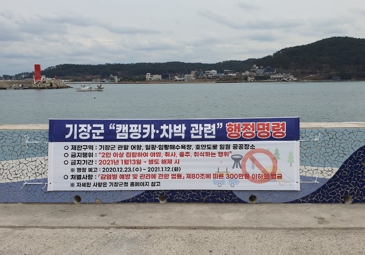 기장군 일광면 이천리 해안가에 설치된 캠핑카, 차박 관련 행정명령 안내 플래카드.(사진제공=부산 기장군)