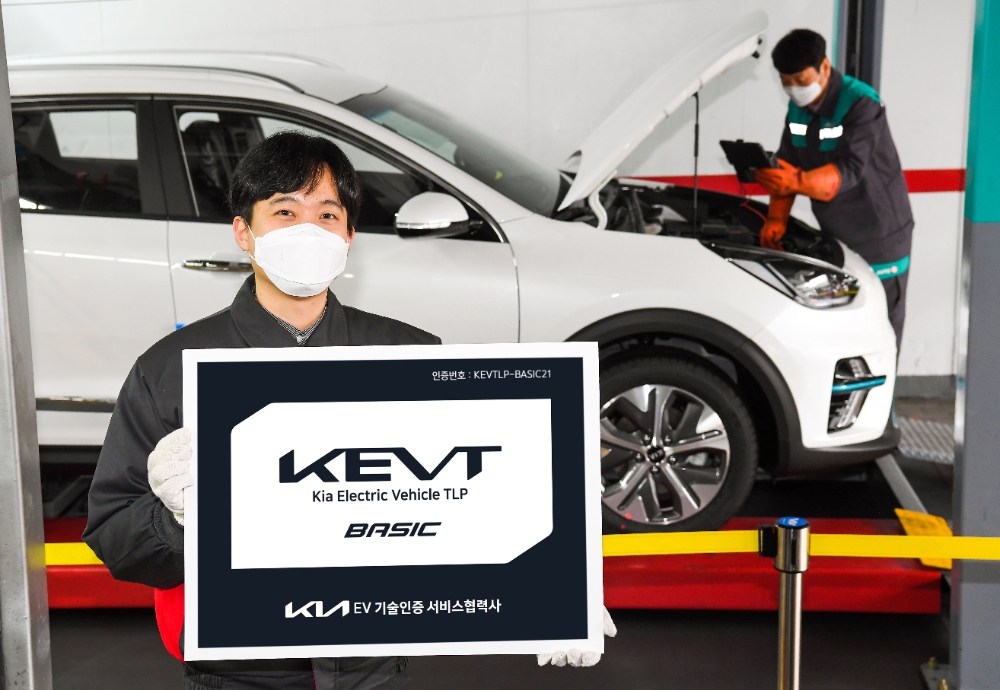 기아 오토큐 정비 엔지니어가 ‘KEVT 베이직’ 인증 현판을 선보이고 있다. 이 인증 현판이 있는 오토큐에서는 전문적인 전기차 정비를 받을 수 있다.(사진=기아)