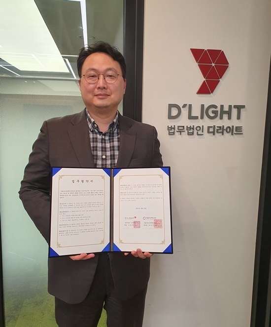 최재욱 변호사가 업무협약서를 내보이며 기념촬영.(사진제공=법무법인 디라이트)