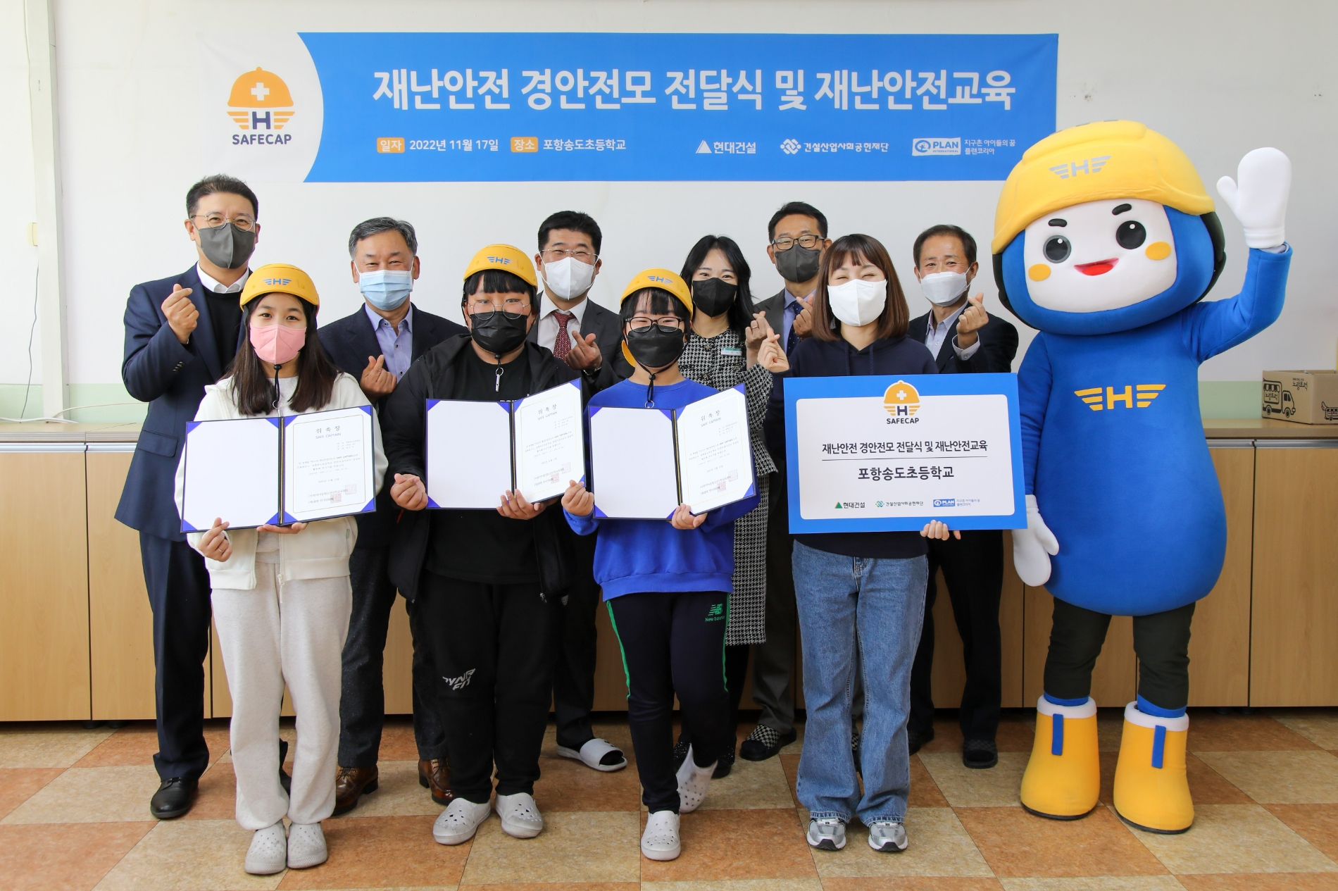 (왼쪽부터) 현대건설 문제철 상무, 건설산업사회공헌재단 오기종 부이사장, 송도초 교장선생님, (맨 오른쪽) 플랜코리아 김병학 본부장이 ‘재난안전 경안전모’ 전달식을 진행하고 있다.(사진=현대건설)