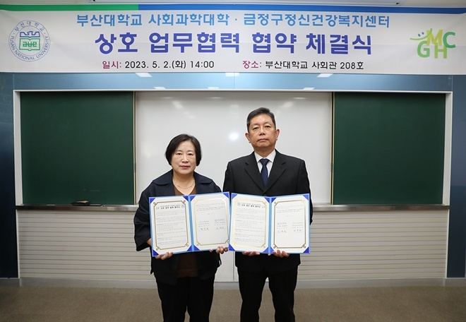 최숙희 금정구정신건강복지센터장과 이재식 부산대 사회과학대학장이 업무협약서를 내보이며 기념촬영.(사진제공=부산대)