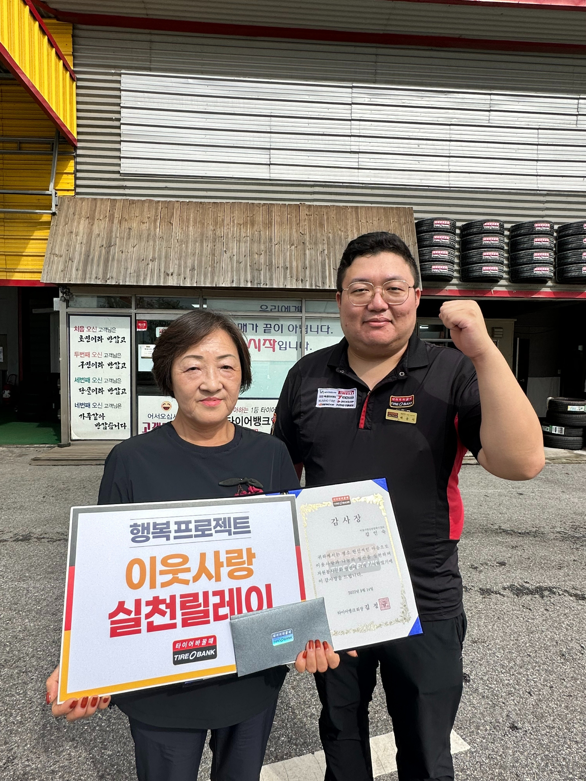 지난 14일 충북 충주시 칠금동에 위치한 타이어뱅크 북충주점에서 감사장과 타이어 교환권 증정 후 김인숙씨(좌)와 타이어뱅크 북충주점 배종석 사업주(우)가 기념 촬영을 하고 있다.(사진=타이어뱅크)