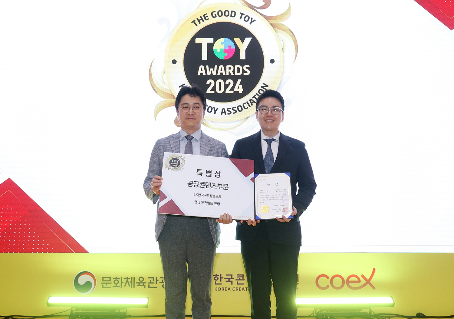 LX한국국토정보공사가 제작한 캐릭터 굿즈 ‘랜디 안전벨트 인형’이  ‘제10회 대한민국 토이어워드’에서 공공콘텐츠부문 특별상을 수상했다. LX 홍보처 방윤식 과장(오른쪽)과 장난감발전소 윤대진 소장이 기념촬영을 하고 있다. (사진=LX한국국토정보공사)