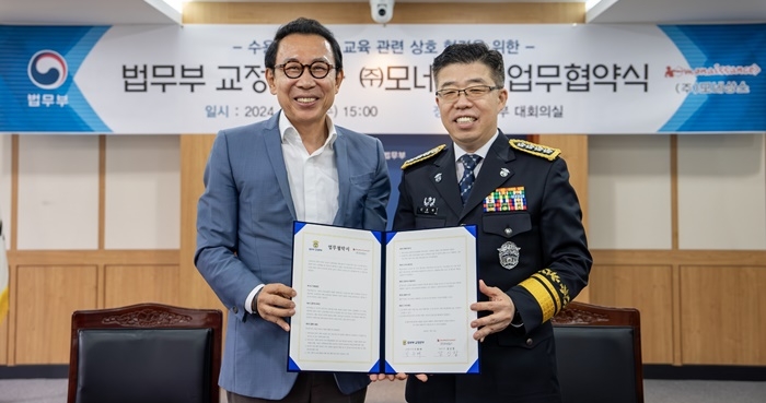 모네사으 강신장 대표와 신용해 교정본부장이 업무협약서를 내보이며 기념촬영.(사진제공=법무부)