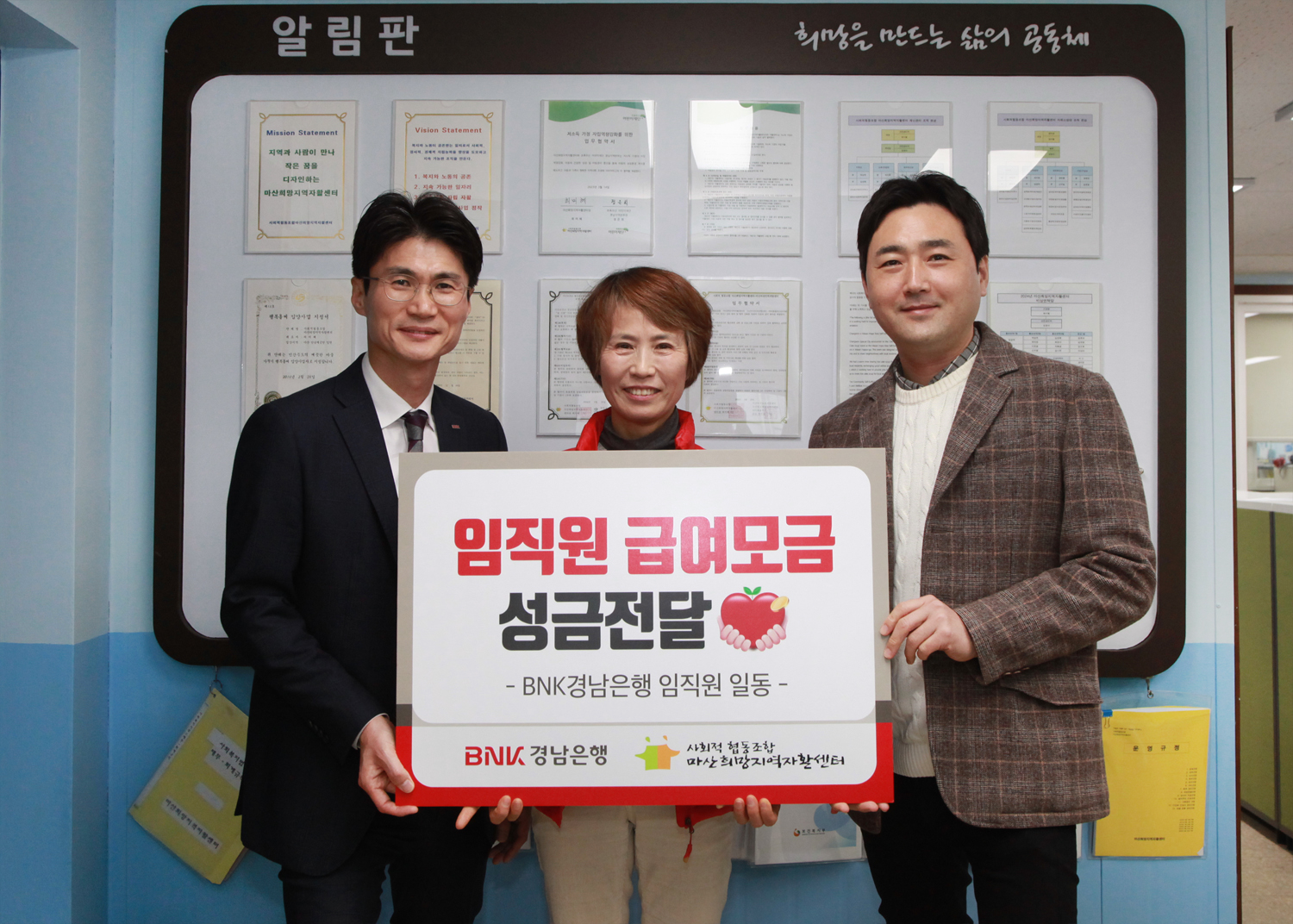 BNK경남은행 김지훈 팀장(사진 오른쪽 첫번째)과 신진욱 지점장이 마산희망지역자활센터 최미혜 센터장에게 ‘백합나눔회 성금 기탁 증서’를 전달하고 있다. 사진=BNK경남은행