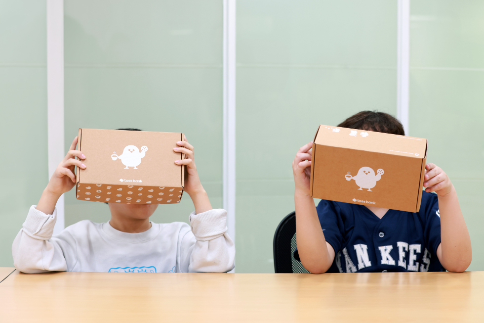 가정폭력쉼터 내 아이들이 '토스뱅크 응원키트'를 들고 빠른 일상 회복을 바라며 얼굴을 가린 채 사진을 찍고 있다. 쉼터 내 거주 중인 피해자들은 가해자로부터의 반복적인 피해를 막기 위해 외부와 단절된 생활을 하고 있다. 사진=토스뱅크