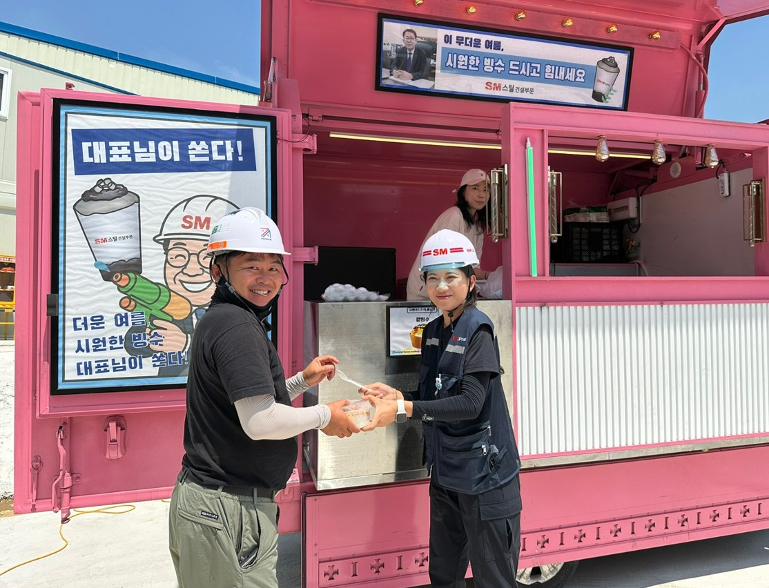 SM스틸 건설부문의 경기 용인시 양지지구 공동주택 신축공사 현장 근로자들이 지난달 25일 푸드트럭에서 팥빙수를 받으며 기념촬영을 하고 있다.(사진=SM그룹)