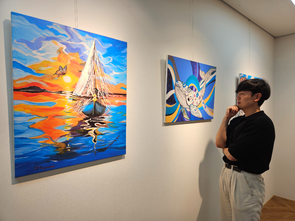 현대제철 직원이 ㈜올모용인 사업장에 걸린 소속 발달장애인 작가들의 작품을 감상하고 있다.(사진=현대제철)