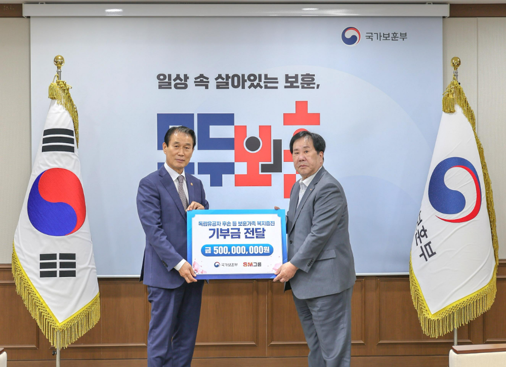 SM그룹 우오현 회장(오른쪽)이 13일 오전 정부세종청사에서 열린 국가보훈부의 전 국민 보훈 기부 프로젝트 ‘모두의 보훈 드림’ 후원금 전달식에서 권오을 장관과 기념촬영을 하고 있다.(사진=SM그룹)