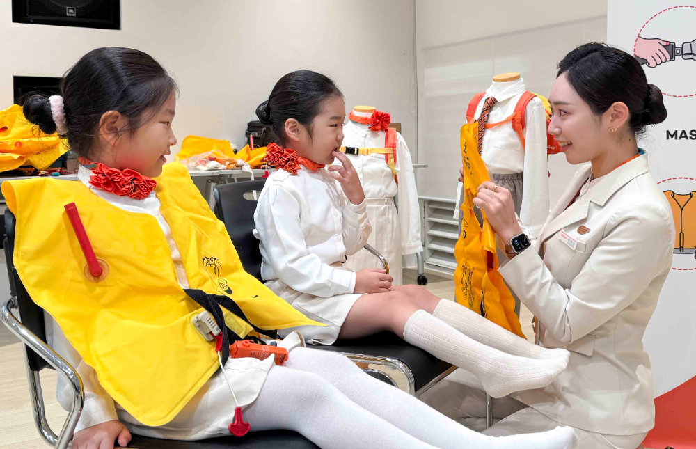 제주항공 객실승무원들이 11월 16일 스타필드마켓 일산점에서 진행된 ‘제주항공과 함께하는 어린이 항공안전체험교실’에서 어린이에게 비상상황 발생시 구명조끼를 착용하는 방법을 가르쳐 주고 있다.(사진=제주항공)