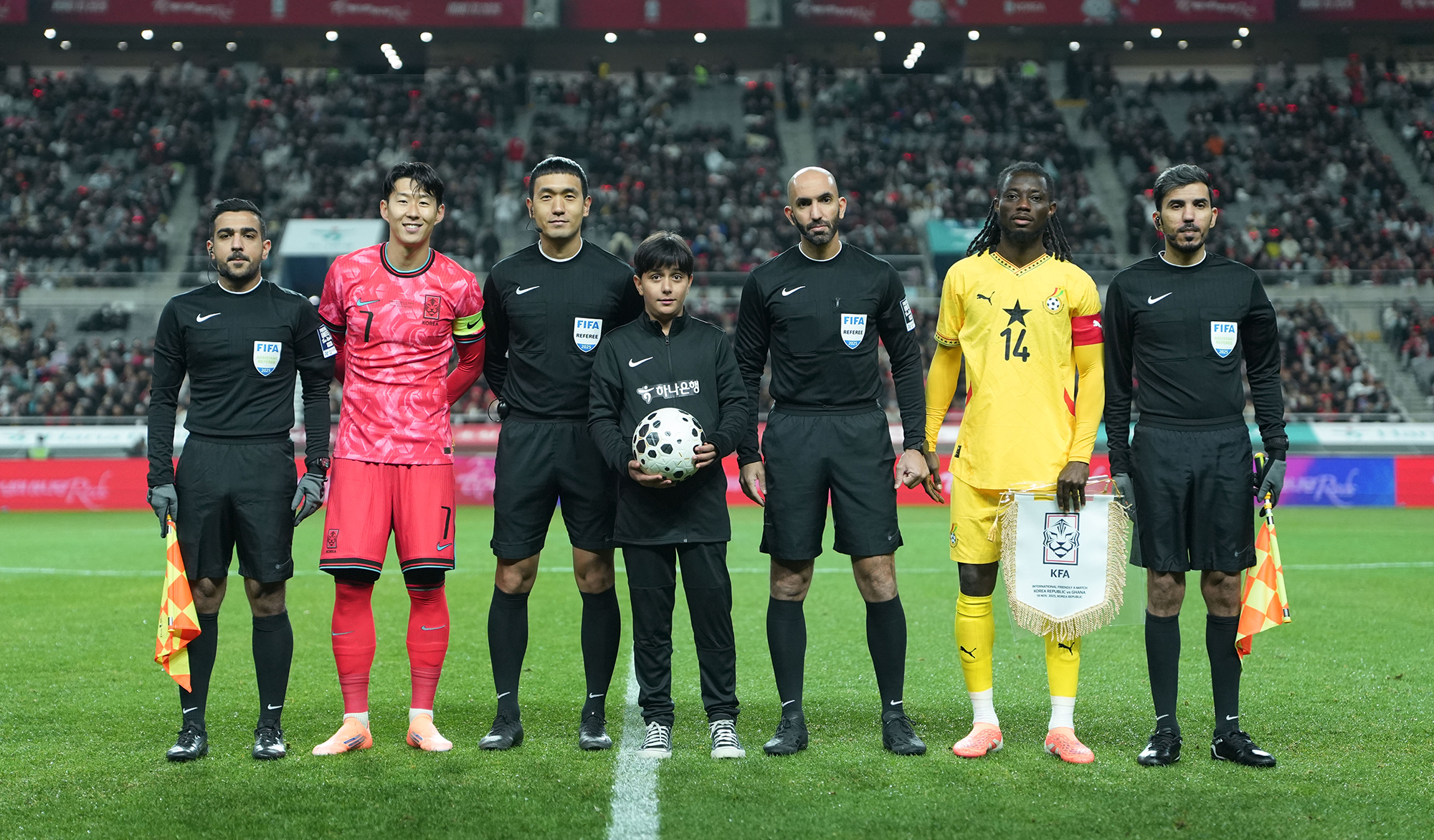 하나은행은 지난 18일 서울월드컵경기장에서 열린 대한민국과 가나의 축구 국가대표팀 A매치 경기에서 이주배경 가정 아동·청소년들에게 '매치볼 키드'와 '기수단'으로 참여할 수 있는 특별한 체험 기회를 제공했다고 밝혔다.이날 경기 시작에 앞서 아프가니스탄 출신 '매치볼 키드' 마시(Masih)가 양 팀 주장 및 심판진과 함께 기념촬영을 하고 있다. 사진=하나은행